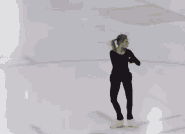 a woman is standing on a ice rink wearing black pants and a black top .