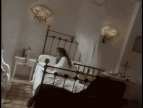 a woman laying on a bed with a cross on the wall