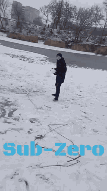 a man standing in the snow with the word sub-zero written in blue