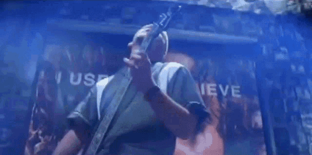 a man is playing a guitar in front of a large poster that says i use to believe