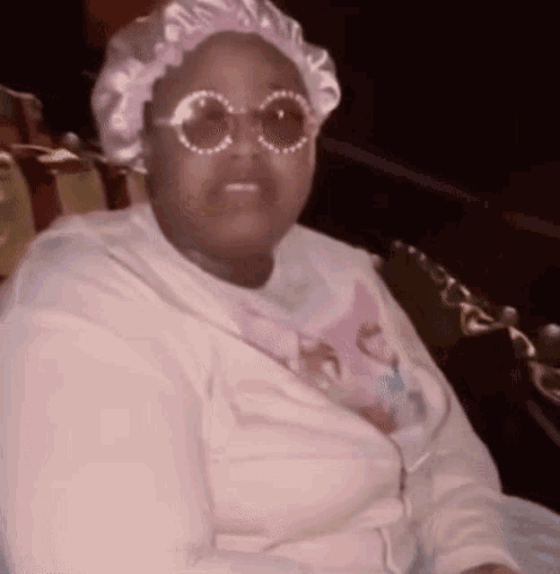 a woman wearing sunglasses and a hat is sitting on a chair .