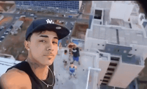 a young man wearing a ny hat takes a selfie