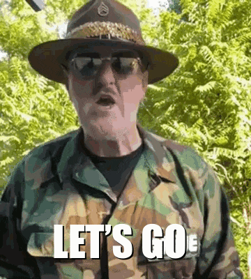 a man wearing a hat and sunglasses is standing in front of trees and says let 's go .