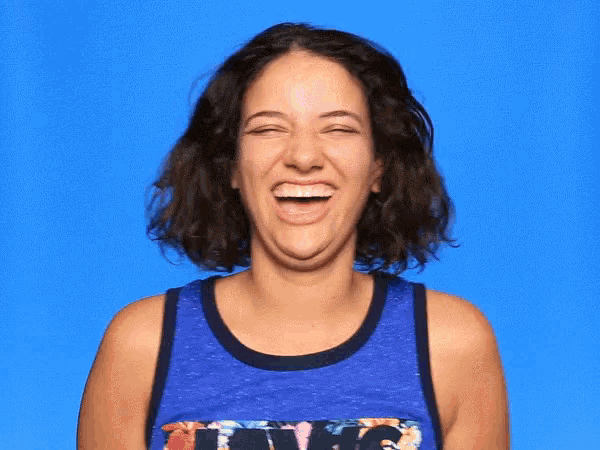 a woman wearing a blue tank top with a floral print is laughing