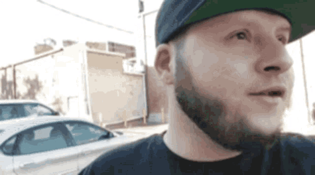 a man with a beard wearing a hat and a black shirt .