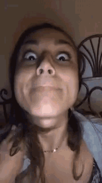 a woman is making a funny face with her mouth open while sitting on a bed .