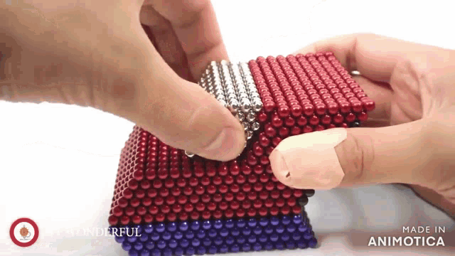 a person is holding a cube made of red white and blue balls