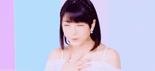 a woman in a white off the shoulder top is smiling and holding her hands on her chest .