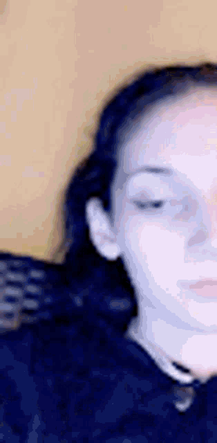 a close up of a woman 's face with her eyes closed and her hair in a ponytail .