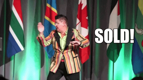 a man in a striped jacket is dancing in front of flags and the word sold is on the screen behind him