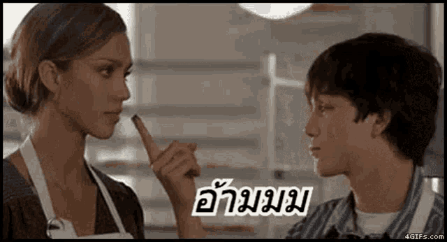 a man and a woman are looking at each other in a kitchen and the woman is pointing at the man .