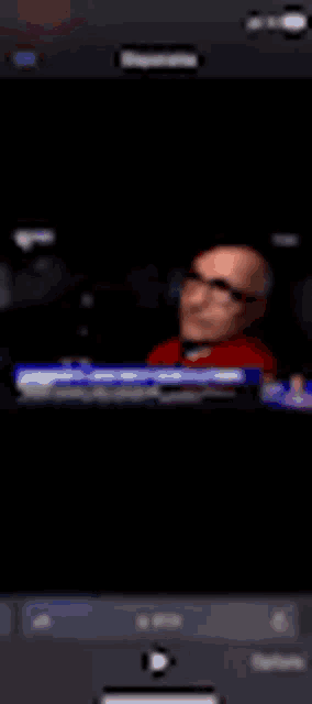a blurry picture of a man wearing glasses on a tv screen