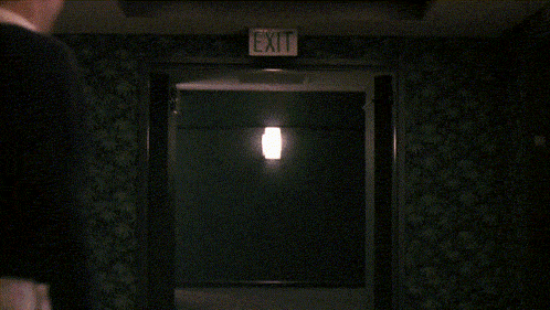 a man wearing a black sweater and a white shirt is standing in a dark room