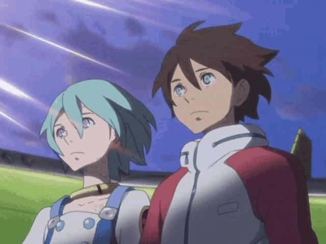 a boy and a girl are standing next to each other and the girl has the letter t on her jacket