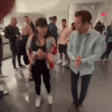 a man and a woman are walking in a crowded room .