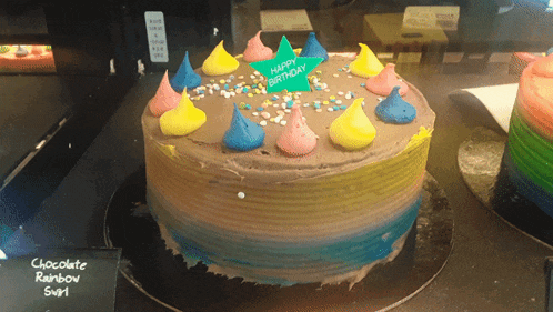 a chocolate rainbow cake with sprinkles and a sign that says happy birthday
