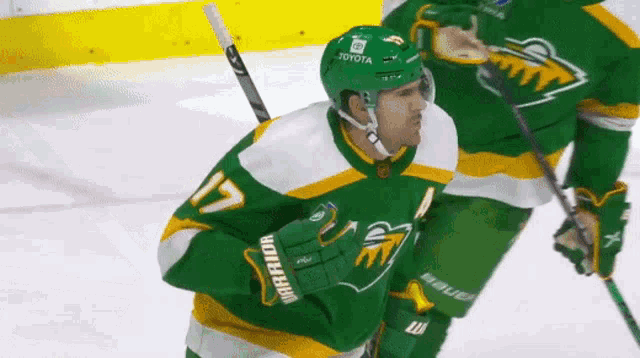 a hockey player wearing a green jersey that says warrior