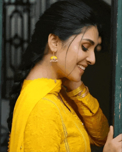 a woman in a yellow dress is smiling and looking down