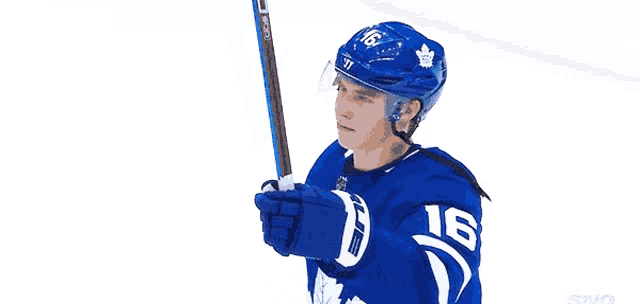 a hockey player with the number 16 on his jersey holds a hockey stick