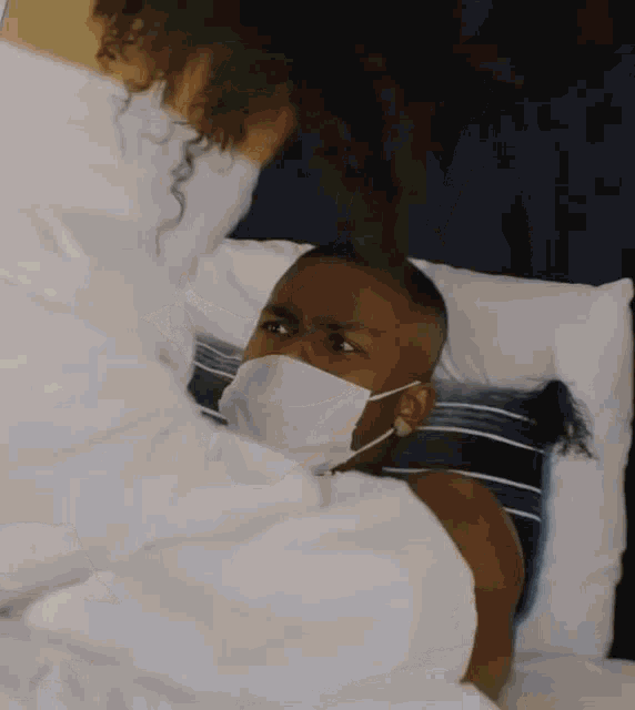 a man wearing a face mask is laying in bed .