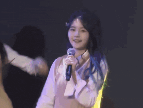 a girl with blue hair holds a microphone in her hand