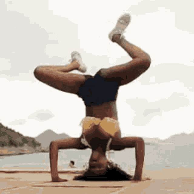 the woman is doing a handstand on the beach .