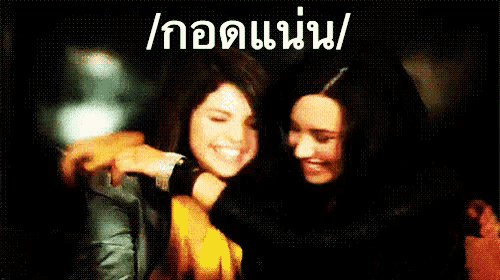 two women hugging each other in a dark room with a foreign language written on the bottom right corner