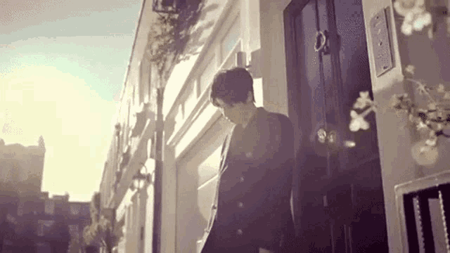 a man in a suit is standing in front of a building with a black door .