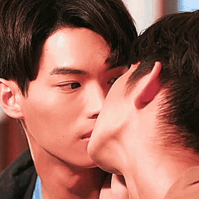 a man is kissing another man on the cheek .