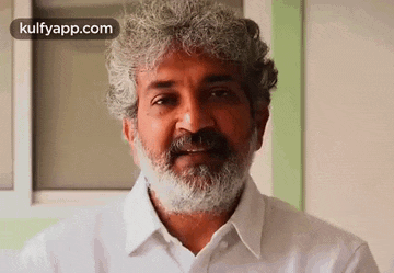 a man with a beard and gray hair is wearing a white shirt .