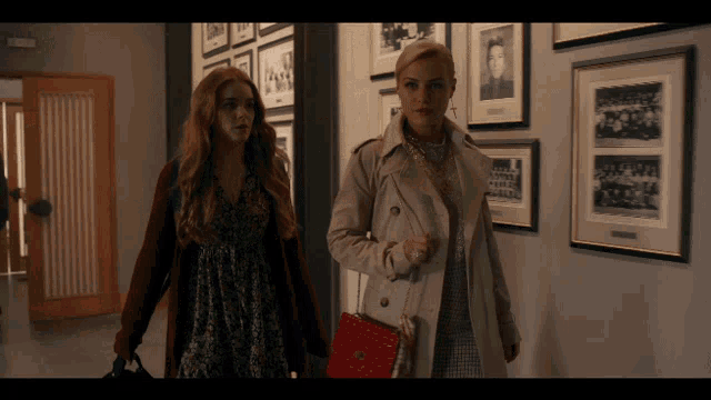 a woman in a trench coat stands next to a woman in a dress