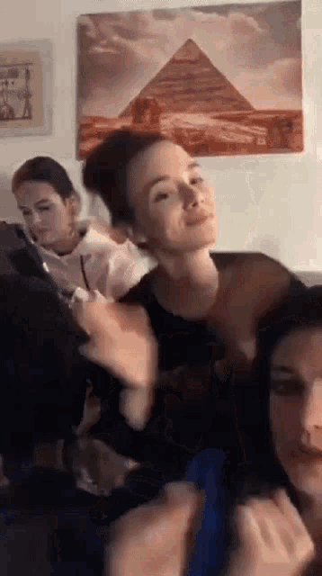 three women are sitting on a couch in front of a pyramid .