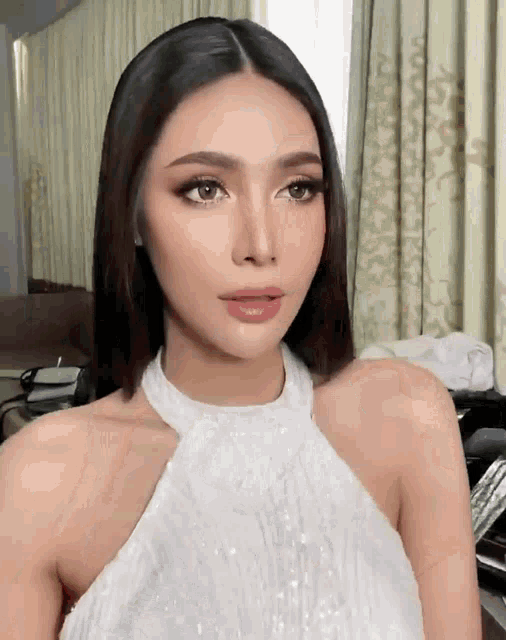 a woman is wearing a white halter top and looking at the camera