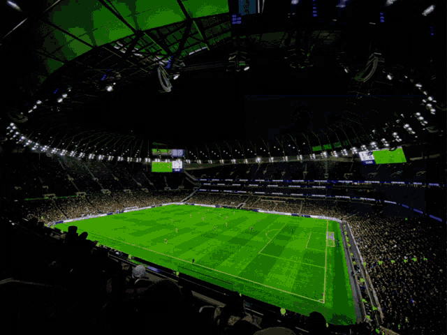 a soccer game is being played in a stadium with a large screen that says ' tottenham hotspur ' on it