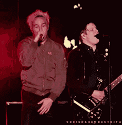 a man singing into a microphone while another man plays a guitar on stage