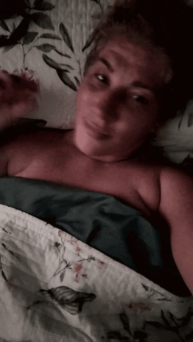 a woman laying on a bed with a floral comforter