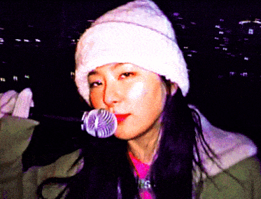 a woman wearing a white hat is blowing bubbles with a microphone