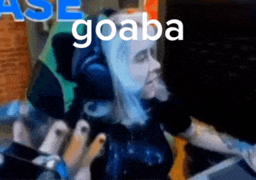 a woman wearing headphones is sitting in front of a computer screen with the word goaba written on the bottom .