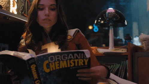 a woman is reading a book on organic chemistry