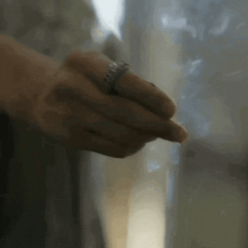 a close up of a person 's hand with a ring on their finger .