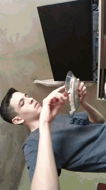 a young man in a blue shirt is looking at a plate