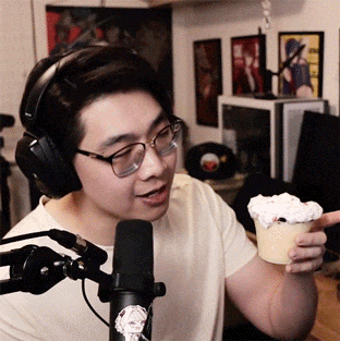 a man wearing headphones is holding a cup of whipped cream