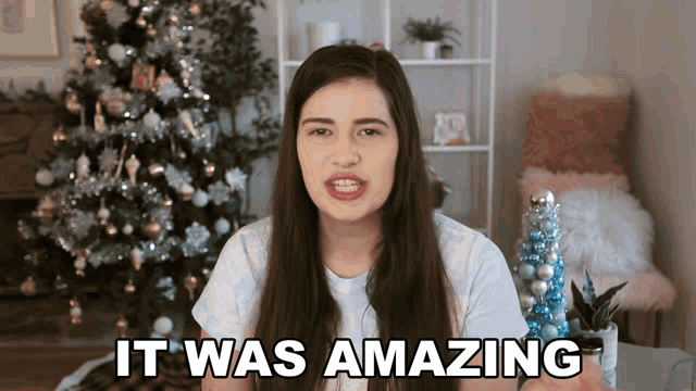 a woman is standing in front of a christmas tree and says " it was amazing "