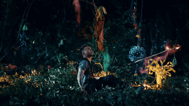 a man sitting in the woods holding a stick