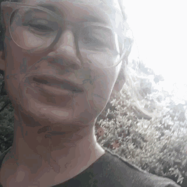 a woman wearing glasses and a black shirt smiles