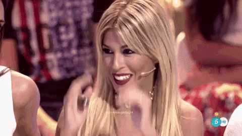 a woman with long blonde hair is smiling and laughing while wearing a microphone on her head .