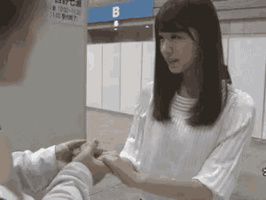 a woman in a white shirt is holding a man 's hand in front of a sign that says b