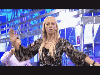 a woman with blonde hair is dancing in front of a blue wall