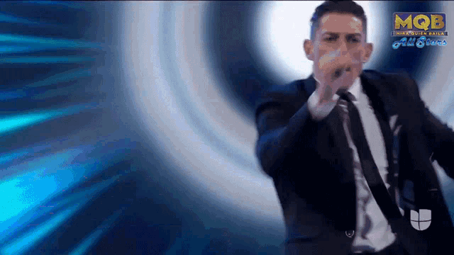 a man in a suit and tie is dancing in front of a screen that says mqb