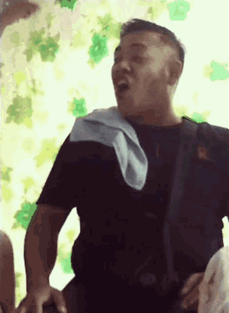 a man with a blue towel around his neck is making a funny face .
